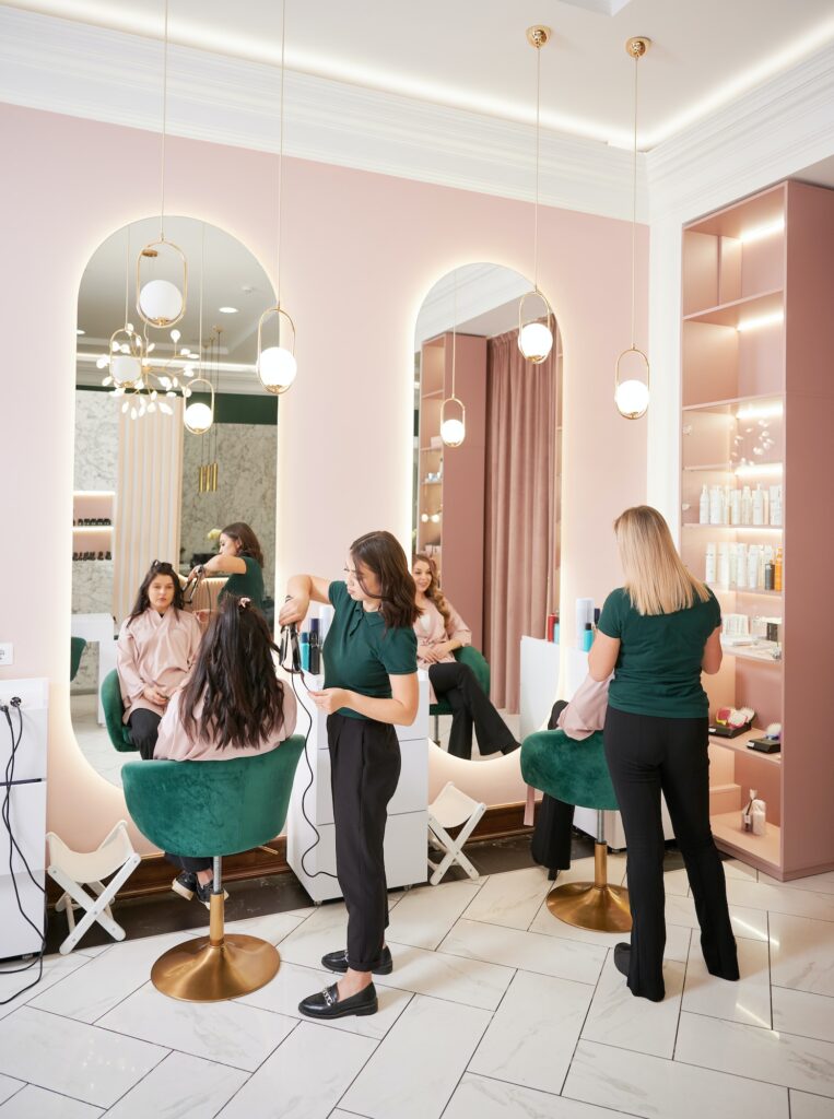 Hairdressers styling women hair in beauty salon.